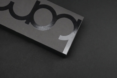 Spot UV creates contrast and shine on black cardboard surface.